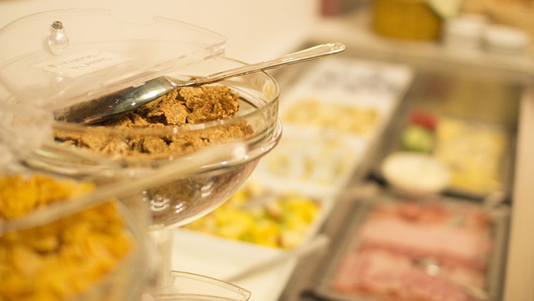 Unser großzügiges Frühstücksbüffet mit Müsli, Jogurt, Obstsalat, Aufschnitten, hausgemachten Marmeladen und Brot und Gebäck, © Hotel Holzinger